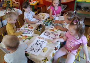 Dzieci przy stoliku kolorują misie.